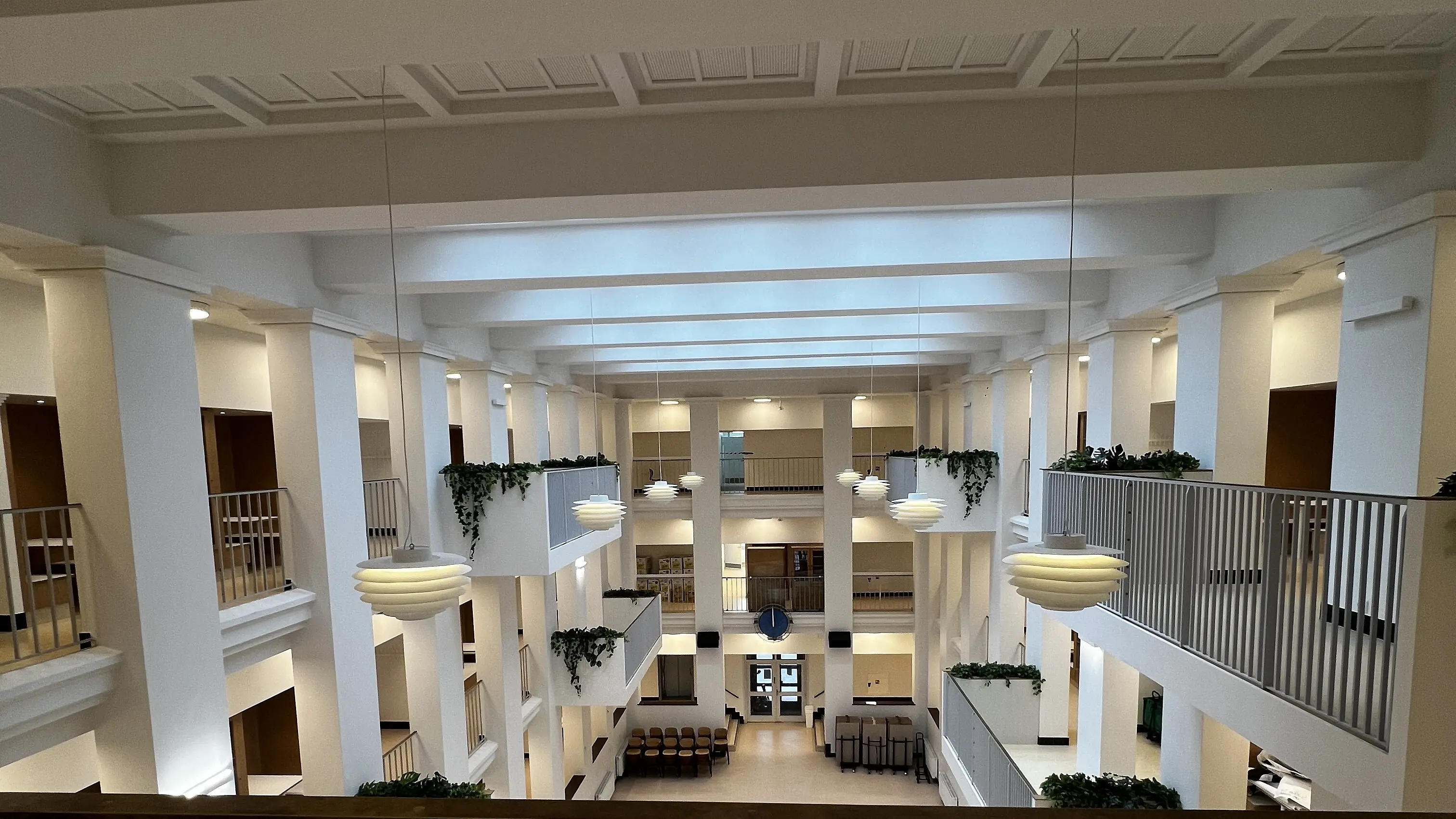 Nyrenoveret aula med altangange, planter og pendelbelysning